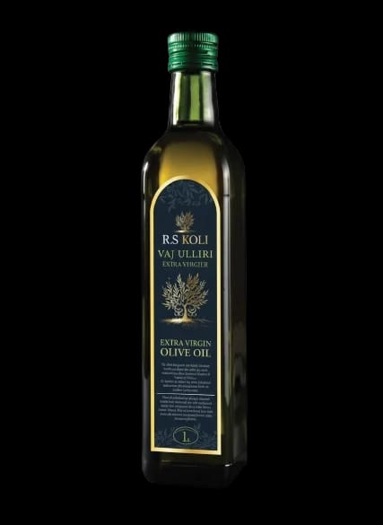 Dark glass bottle of R.S KOLI extra virgin olive oil with a sealed cap on a wooden shelf